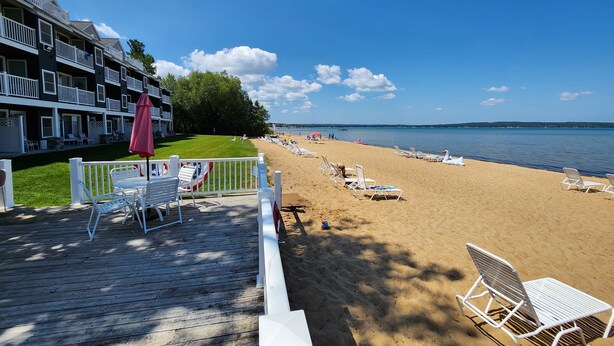 Ein Strand mit weißen Liegestühlen und einem Holzdeck mit weißen Geländern.