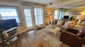 A living room with a TV, sofa, coffee table, and a rug.