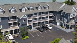 A multi-story hotel with a parking lot, balconies, and a view of the water. - Northern Michigan Charm, North Shore Inn Condo 209 (Traverse City)