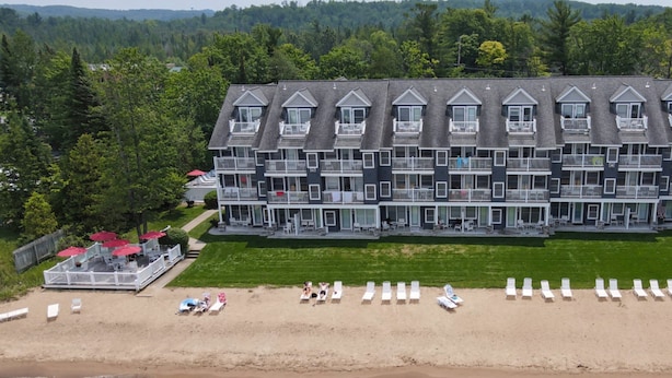 A large, multi-story hotel with a symmetrical facade, multiple balconies, and a beach area with sun loungers. - Northern Michigan Charm, North Shore Inn Condo 209 (Traverse City)