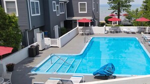 A rectangular swimming pool with a diving board, surrounded by lounge chairs and umbrellas. - Northern Michigan Charm, North Shore Inn Condo 209 (Traverse City)