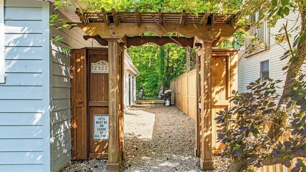 Ein Eingangsbereich mit einer Holzw pergola und einem Kiesweg, der zu einem Haus führt.
