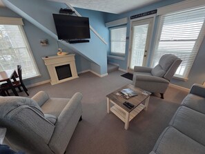 A living room with a fireplace, a flat-screen TV, and a sofa.