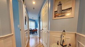A hallway with wooden flooring, white doors, and a dining area in the background. - Amazing Views, Private Balcony! Recent Remodel - North Shore Inn Condo 301 (Traverse City)