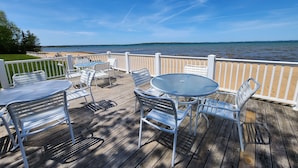 A wooden deck with white metal furniture overlooking a lake. - Stunning Views, Private Master Suite - North Shore Inn Condo 306 (Traverse City)