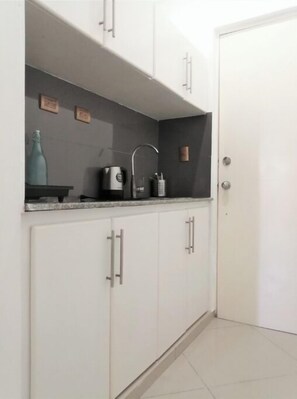 Compact kitchen area with a stainless steel sink, coffee maker, and electric kettle.