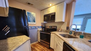 A compact kitchen with a refrigerator, microwave, stove, oven, and dishwasher.