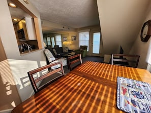 A dining area with a wooden table and chairs, a checkered tablecloth, and a quilt on the table.