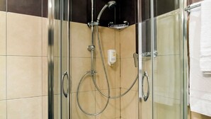 A glass-enclosed shower stall with a handheld showerhead, a wall-mounted faucet, and a control panel. - Florella Residences 2 pièces duplex Achard (Cannes)