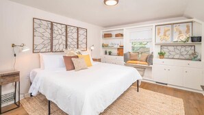 Un dormitorio con una cama grande, mesitas de noche, un aparador y decoración en la pared.