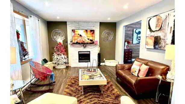 Een moderne woonkamer met een open haard, een kerstboom en een bruine leren bank.