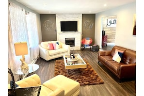 A modern living room with a fireplace, a sofa, a coffee table, and a leather couch.