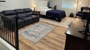 A loft-style bedroom with a bed, a desk, a sofa, and a staircase. - Adorable Brand New Studio Barn Loft with Full Kitchen and Bath (Provo)