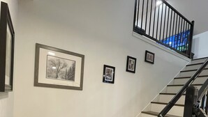 A staircase with wooden steps and a black railing, leading to a landing with three framed pictures on the wall. - Adorable Brand New Studio Barn Loft with Full Kitchen and Bath (Provo)