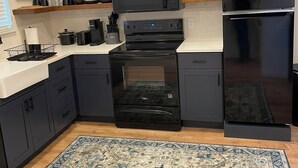 A modern kitchen with dark cabinetry, a built-in microwave, a double oven, and a black refrigerator. - Adorable Brand New Studio Barn Loft with Full Kitchen and Bath (Provo)