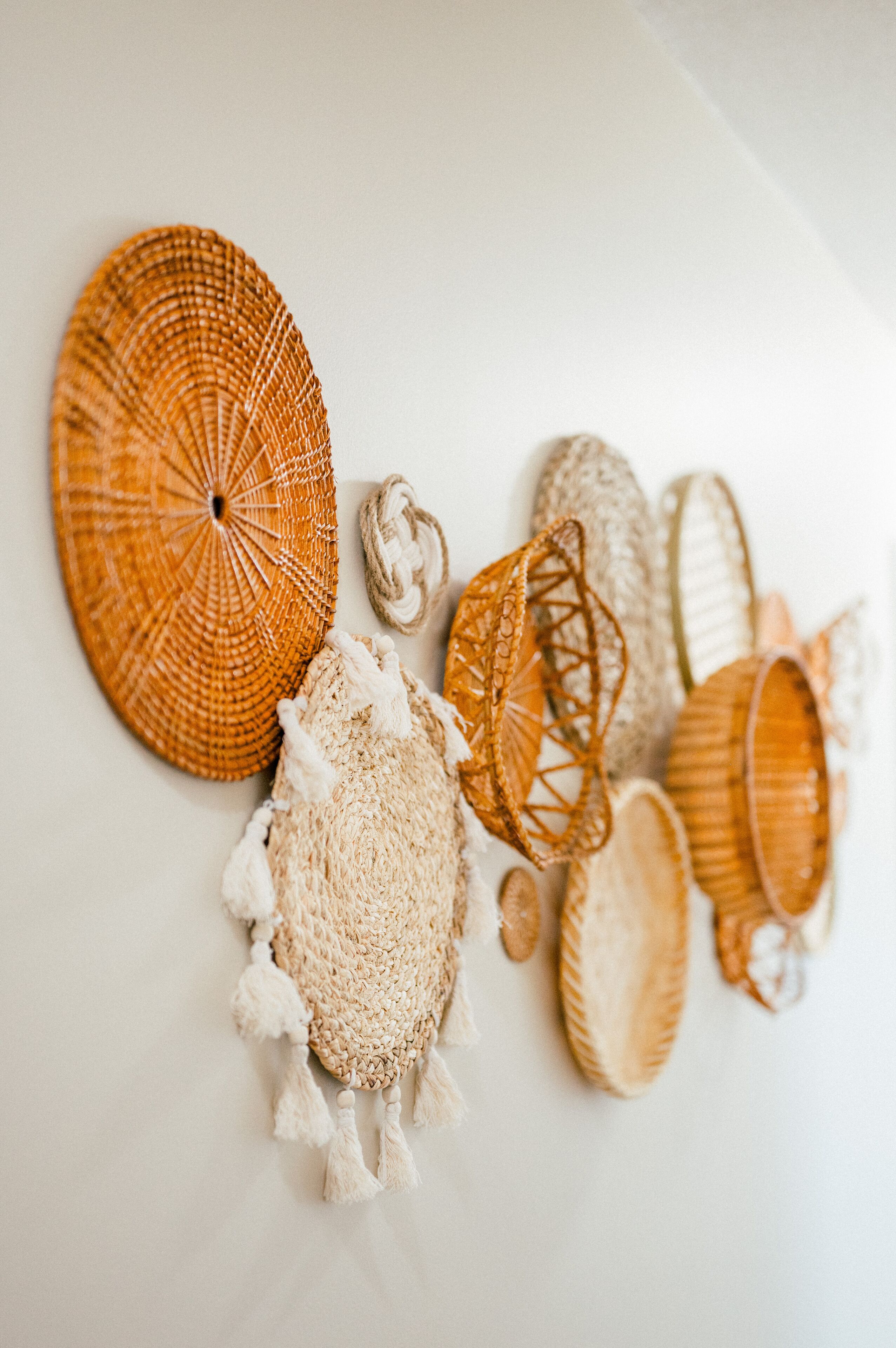 A collection of woven baskets and a macrame wall hanging on a plain wall.