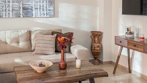 A modern living room with a beige sofa, a wooden coffee table, decorative vases, and a television mounted on the wall.
