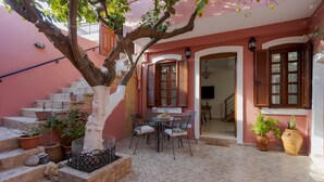 A courtyard with a dining table and chairs, a staircase, and potted plants.
