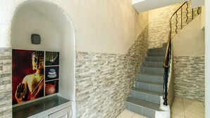 A staircase with stone walls and a handrail, leading to an upper floor. - Florella Residences 2 pièces supérieur République (Cannes)