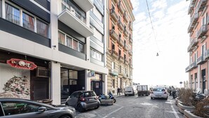 A street view with a pizzeria on the left, parked cars, and a building with balconies. - Via Niccolò Tommaseo 4 - appartamento 2 (Napoli)