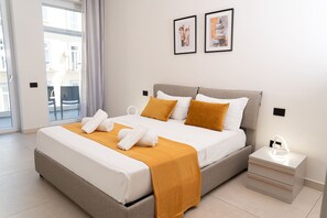 Une chambre d’hôtel moderne avec un grand lit, une table de chevet, une commode et deux œuvres d’art encadrées accrochées au mur.