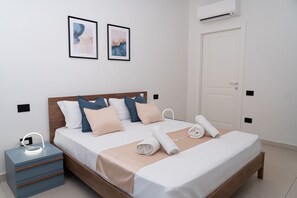 A neatly made bed with a wooden headboard, a bedside table with drawers, and two framed artworks on the wall. - Via Niccolò Tommaseo 4 - appartamento 2 (Napoli)