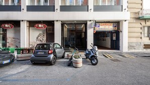 A building with a garage sign, a parked car, and a scooter. - Via Niccolò Tommaseo 4 - appartamento 2 (Napoli)