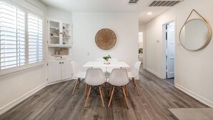A dining area with a white table and chairs, a decorative wall piece, and a built-in cabinet with shelves.