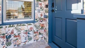 A blue door with a welcome mat and a window with a grid pattern.