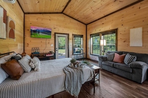 Un acogedor interior de cabaña con una cama, un sofá y una zona de comedor.
