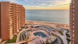 Un resort con diversi edifici a più piani, una piscina centrale con lettini e vista sull'oceano.