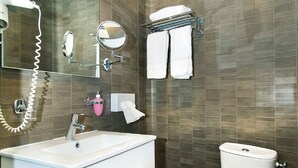 Un baño moderno con lavamanos, espejo y retrete blancos.