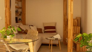 Una camera accogliente con soffitto in legno, un tavolino in vetro, mobili in vimini e una libreria.