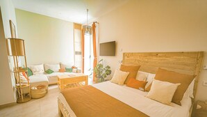 Una camera da letto con un letto grande, un divano, un tavolino e una pianta in vaso.