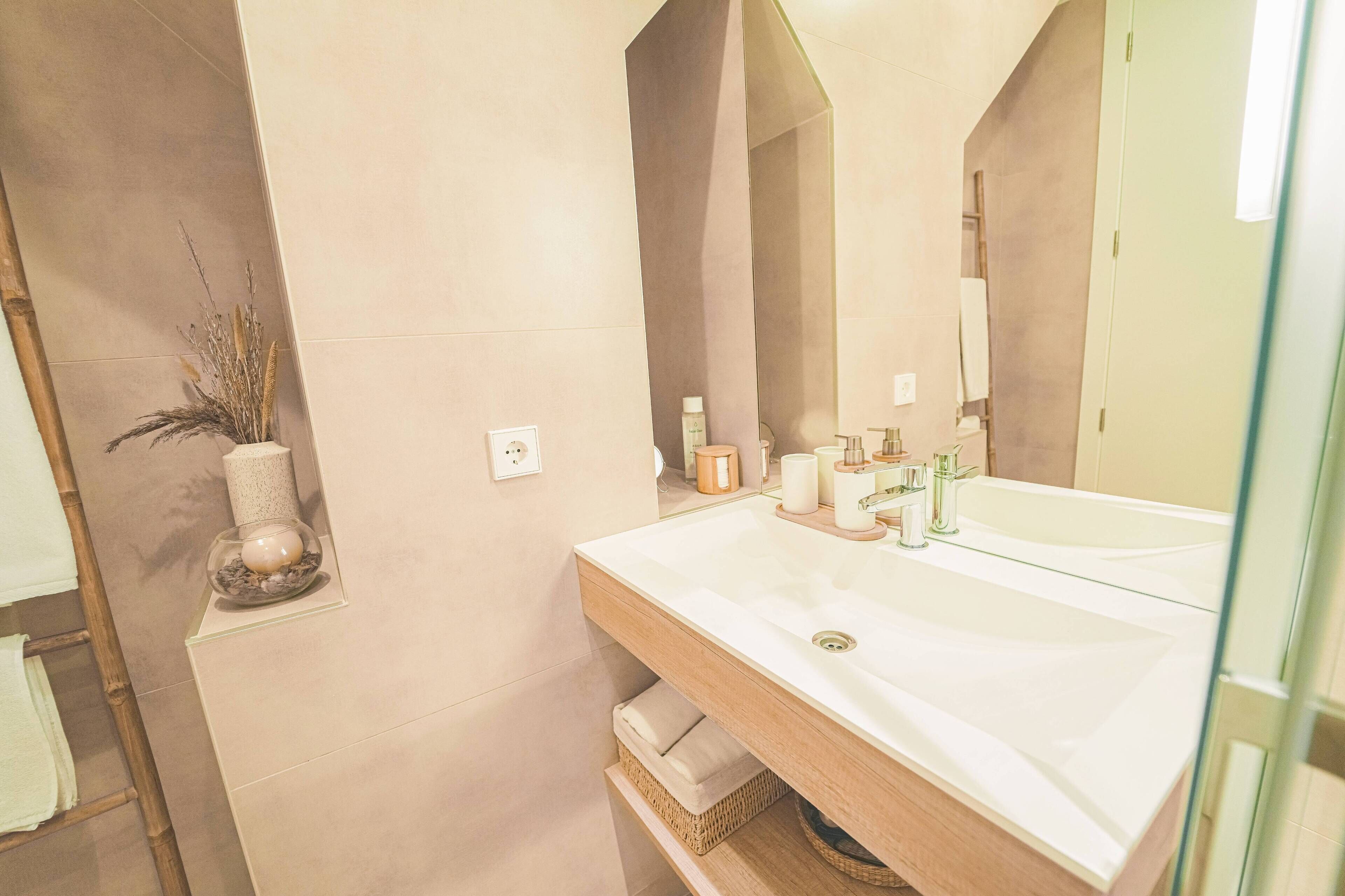 Un baño moderno con un espejo grande, un lavabo blanco y un mueble de tocador de madera.