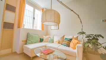 Ein gemütliches Wohnzimmer mit einem weißen Sofa, einem Glastisch und einer Pendelleuchte.