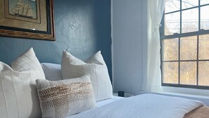 A bedroom with a bed, pillows, a framed picture, and a window with a view. - Historic house overlooking Rondout Creek (Kingston)