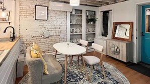 A dining area with a brick wall, white cabinets, and a blue door. - Historic house overlooking Rondout Creek (Kingston)