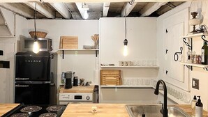 A modern kitchen with a black Galanz refrigerator, a built-in microwave, a gas stove, and a wooden countertop. There are hanging light bulbs and a sink with a black faucet. - Historic house overlooking Rondout Creek (Kingston)