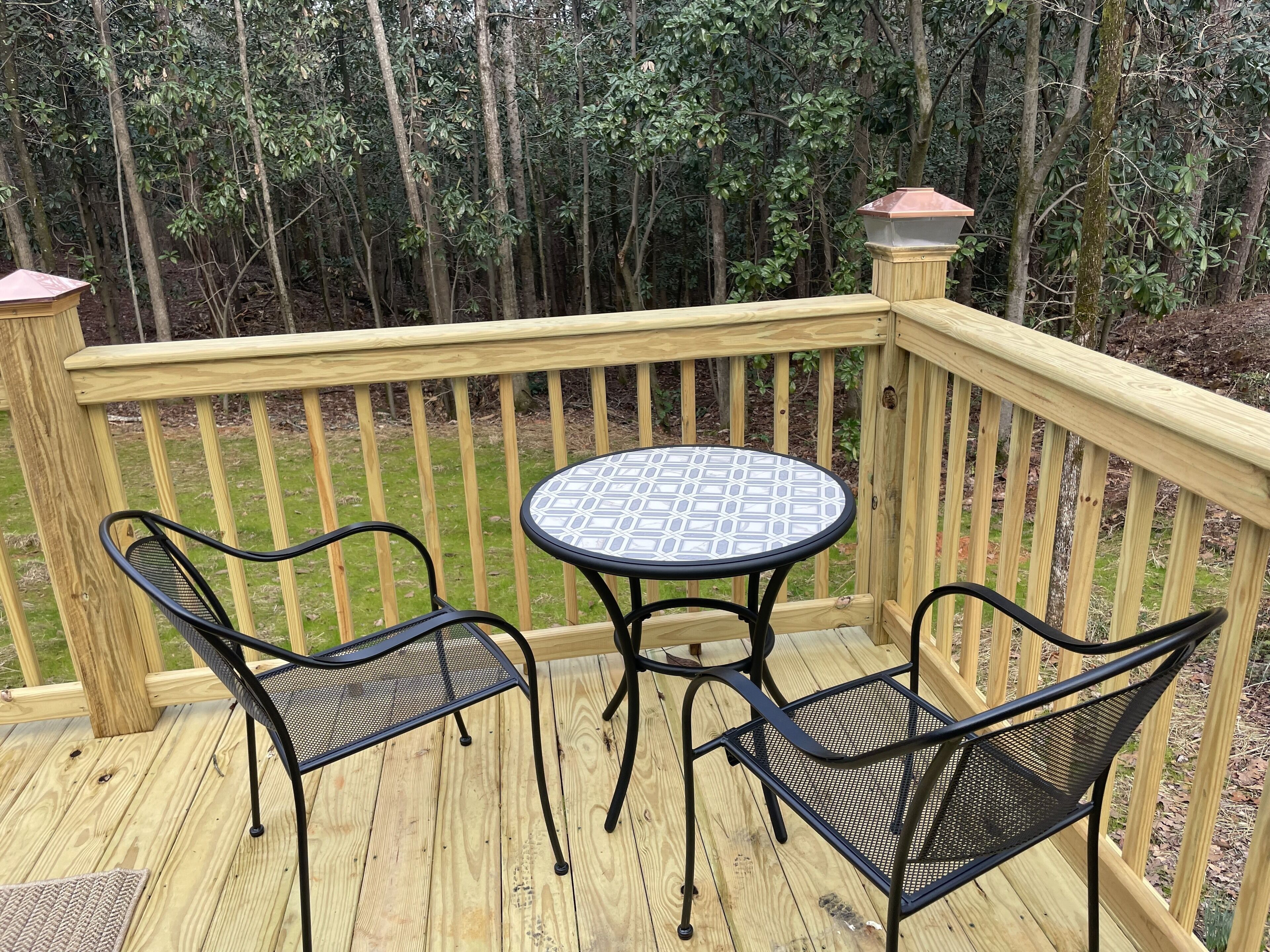 A wooden deck with a round table and two chairs.