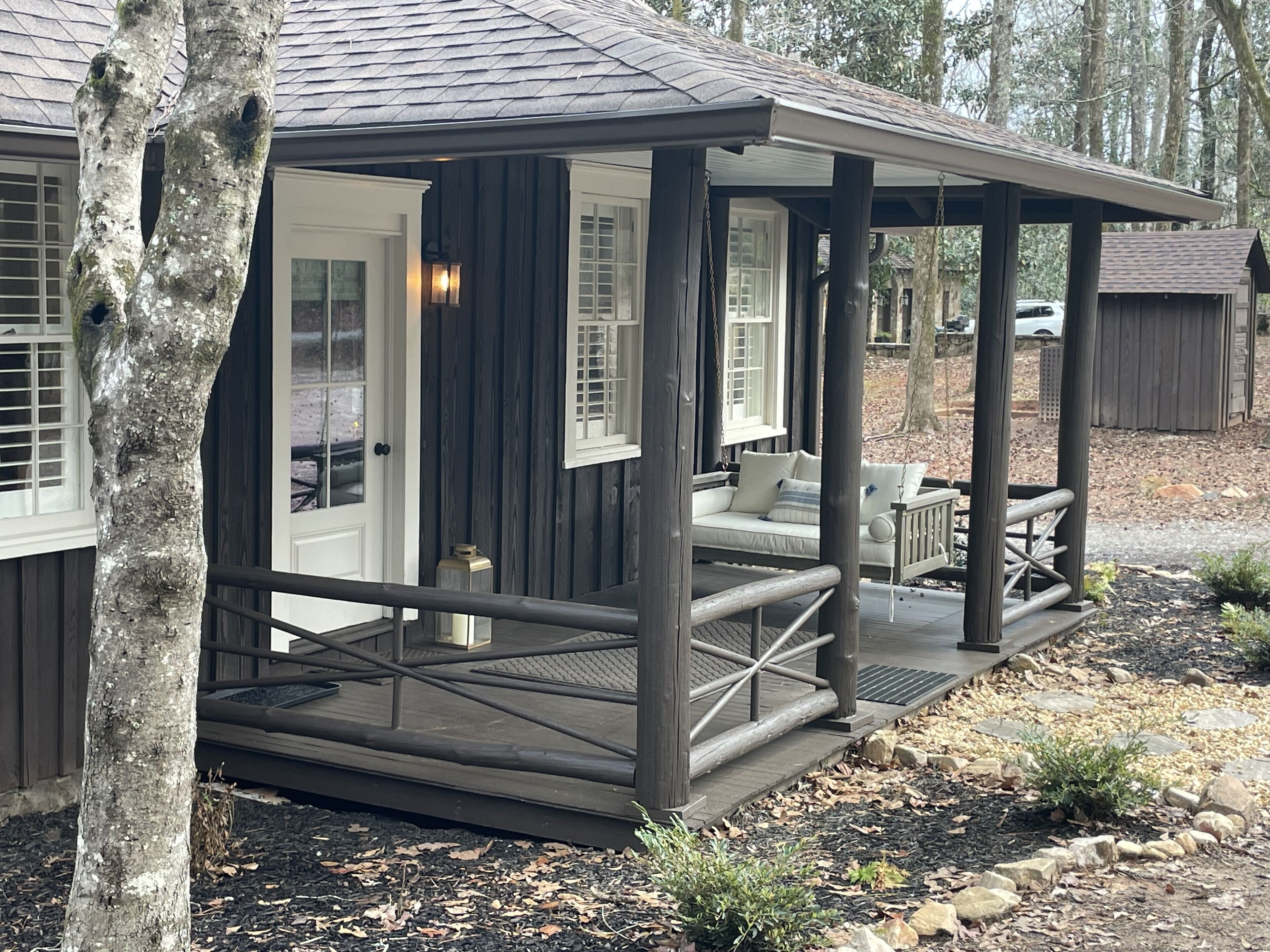 Een houten chalet met veranda, een bank en een schommel.