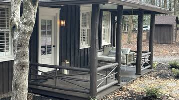 Een houten chalet met veranda, een bank en een schommel.