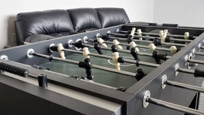 Een tafelvoetbaltafel met een zwart tafelblad en speelfiguren in wit en zwart.