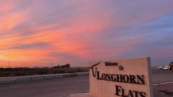 Welkomstbord voor Longhorn Flats, met een zonsondergang op de achtergrond.