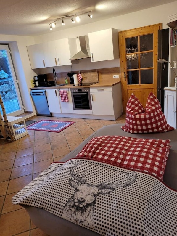 Eine moderne Küche mit weißen Schränken, einem eingebauten Ofen und einer Holztür.