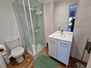 Ein modernes Badezimmer mit einer Duschkabine aus Glas, einem weißen Waschbecken und einer Toilette.