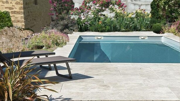 A swimming pool with steps leading up to it, surrounded by a garden with various plants and flowers. - Gîte des Tannières ideal for a successful stay (Pouques-Lormes)