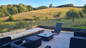 An outdoor patio with wicker furniture, a cushioned sofa, and a lounge chair. - Gîte des Tannières ideal for a successful stay (Pouques-Lormes)