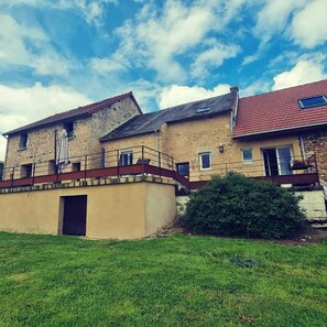 Ein zweistöckiges Gebäude mit einer Steinfassade und einem roten Ziegeldach sowie einem kleinen Balkon.