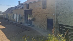 A stone building with a tiled roof, a wooden fence, and a gravel driveway. - Gîte des Tannières ideal for a successful stay (Pouques-Lormes)